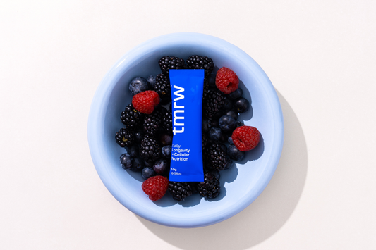 Tmrw daily longevity sachet in a bowl of mixed berries.